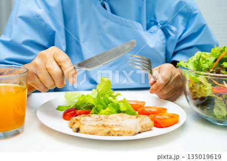 Asian elderly woman patient eating salmon stake and vegetable salad for healthy food in hospital. Asian elderly woman patient eating salmon stake and vegetable salad for healthy food in hospital. 135019619