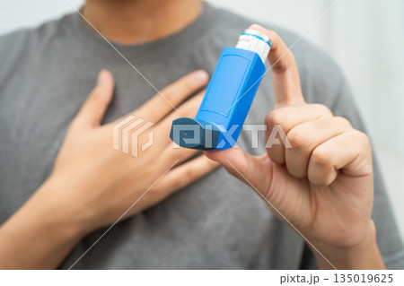 Asthma and chronic obstructive pulmonary disease COPD, Asian young man using metered dose inhaler MDI. Asthma and chronic obstructive pulmonary disease COPD, Asian young man using metered dose inhaler MDI. 135019625