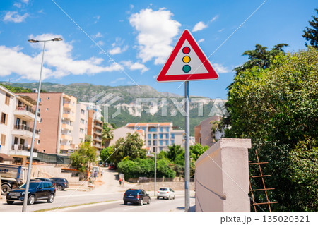 Traffic warning sign near an urban road with residential buildings. Road safety awareness, regulated movement, and visual communication within public transport infrastructure systems. Traffic warning sign near an urban road with residential buildings. Road safety awareness, regulated movement, and visual communication within public transport infrastructure systems. 135020321