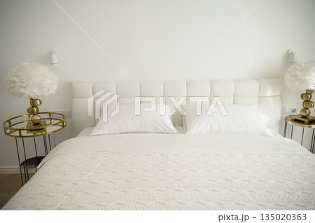 bright bedroom with white pillows with a blanket and a plaid on the bed 135020363