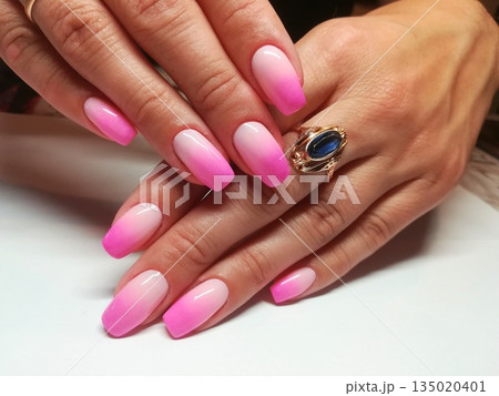 Blending pink ombre gradient on long coffin shaped nails. Transitioning smooth pink to white ombre effect on extended coffin nails adorned with gold ring in elegant manicure display 135020401