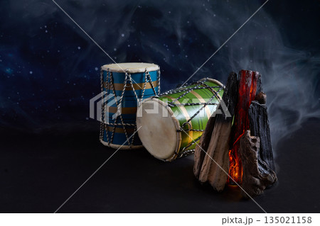 Hand drums with bonfire glowing under starry night sky 135021158