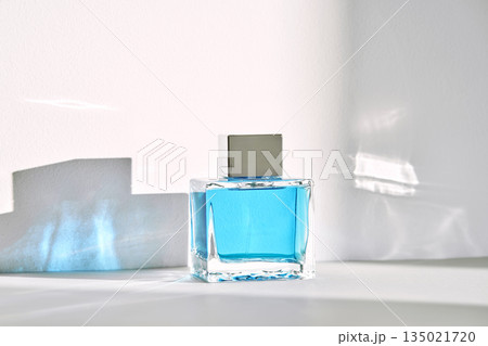 Perfume bottle with blue fragrance standing on white surface Perfume bottle with blue fragrance standing on white surface 135021720