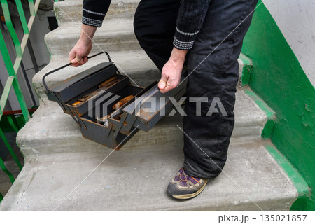 master opens a sliding metal toolbox on the stairs master opens a sliding metal toolbox on the stairs 135021857