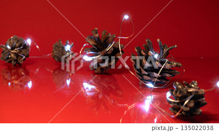 Christmas Pine Cones and Lights on Red Background Christmas Pine Cones and Lights on Red Background 135022038