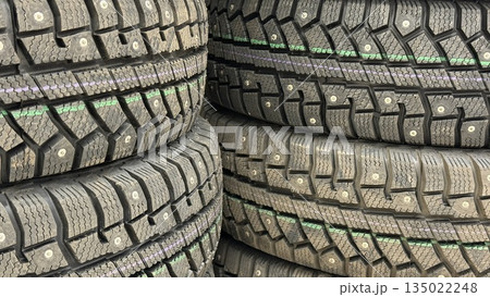 Stacks of studded winter tires arranged closely together, showcasing detailed tread patterns 135022248