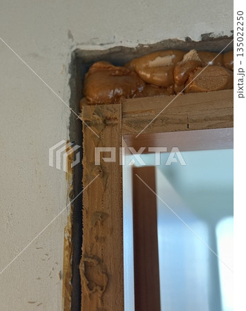Construction detail of doorway with exposed wall insulation and foam showing building process 135022250