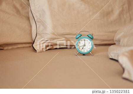 Alarm clock on an unmade bed in the morning light. Alarm clock on an unmade bed in the morning light. 135022381