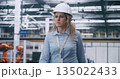 Factory Floor Management, Female Engineer Wearing White Hard Hat and Checking Data 135022433