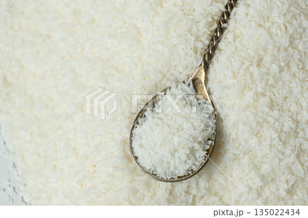 Chopped dried coconut flakes in a macro spoon 135022434