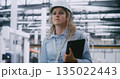 Woman in Safety Helmet Conducts Audit, Swiping Screen of Handheld Tablet to View Production Metrics 135022443