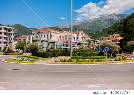 Urban roundabout surrounded by residential buildings and green mountain landscape in Montenegro. City infrastructure planning, everyday mobility, Mediterranean town environment and balanced Urban roundabout surrounded by residential buildings and green mountain landscape in Montenegro. City infrastructure planning, everyday mobility, Mediterranean town environment and balanced 135022754