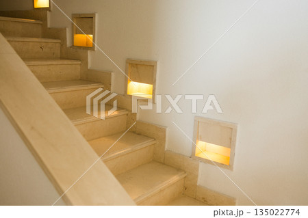Interior staircase with integrated wall lighting and stone steps. Safe movement design, architectural guidance, functional illumination and calm residential circulation space 135022774