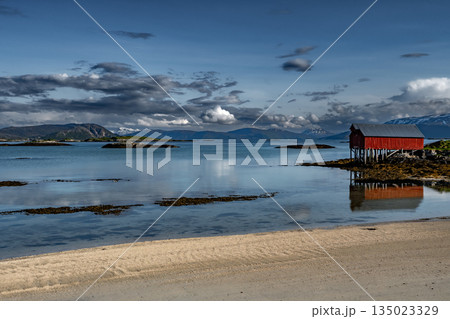 Sandy Beach And Red Hut Cottage In Front Of Mountains On Sommaroy Island At Calm Fjord In Norway 135023329