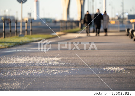 Technical salt scattered over asphalt ground surface for ice crust formation prevention in winter. Technical salt scattered over asphalt ground surface for ice crust formation prevention in winter. 135023926