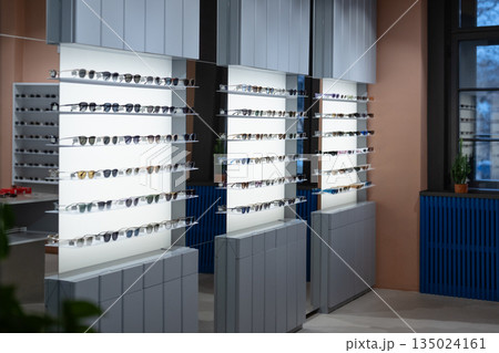 Store selling eyewear fashionable sunglasses, various modern sunshades on display in retail store. 135024161