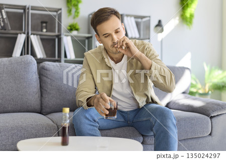 Stressed man drinking alcohol, smoking at home, showing addiction and health risk Stressed man drinking alcohol, smoking at home, showing addiction and health risk 135024297