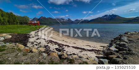 White Sand Beach With Red Hut And Snowy Mountains At Fjord On Lofoten In Norway 135025510