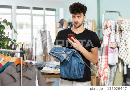 Young shopper scanning jeans tag in outlet store 135026447