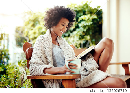 African woman, reading and backyard patio with book and coffee feeling relax and happy. Happiness, black female person and smile in a home garden in the morning with tea outdoor in the sun sitting 135026710