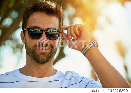 Happy, sunglasses and portrait of a man in an outdoor park while on a summer vacation, adventure or holiday. Smile, confidence and young male person with eyewear standing in a garden on weekend trip. 135026800