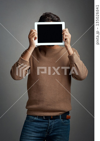 Tablet screen, space and man covering face in studio isolated on a gray background. Touchscreen, hiding and male person with mockup for marketing, advertising and technology for commercial promotion. Tablet screen, space and man covering face in studio isolated on a gray background. Touchscreen, hiding and male person with mockup for marketing, advertising and technology for commercial promotion. 135026841
