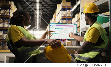 African american warehouse clerks monitors parcel status on package tracking software, managing e-commerce logistics and shipment route to update clients in real time. Order fulfillment. Camera A. African american warehouse clerks monitors parcel status on package tracking software, managing e-commerce logistics and shipment route to update clients in real time. Order fulfillment. Camera A. 135027012