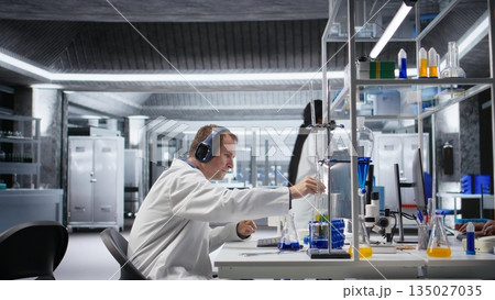 Atypical researcher uses headset for focus music during experiment, distinct approach in laboratory science. Unique scientist combines originality with genetics research at work. Atypical researcher uses headset for focus music during experiment, distinct approach in laboratory science. Unique scientist combines originality with genetics research at work. 135027035