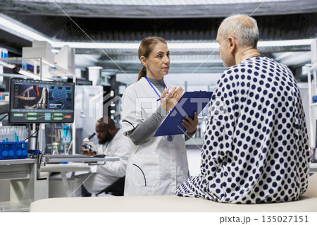 Woman medical specialist testing new drugs on old man in research lab, working on treatment development and examining possible allergic reaction or symptoms. Health progress. 135027151