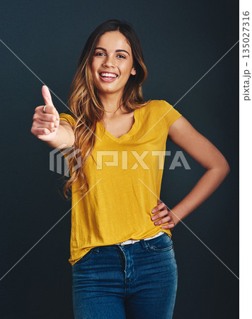 Thank you, portrait and a woman with a thumbs up for success, agreement and yes sign. Smile, like and a lady with a hand gesture isolated on a dark background in a studio for motivation and a goal Thank you, portrait and a woman with a thumbs up for success, agreement and yes sign. Smile, like and a lady with a hand gesture isolated on a dark background in a studio for motivation and a goal 135027316