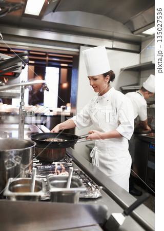 Chef, woman and frying pan in restaurant kitchen, catering service and prepare food for fine dining. Professional, cooking and female person saute meat for meal, diet and nutrition for hospitality. Chef, woman and frying pan in restaurant kitchen, catering service and prepare food for fine dining. Professional, cooking and female person saute meat for meal, diet and nutrition for hospitality. 135027536