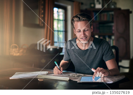 College homework, studying and a man with a tablet for research, education and elearning. Smile, working and a male student with technology for information and planning for an exam in a house College homework, studying and a man with a tablet for research, education and elearning. Smile, working and a male student with technology for information and planning for an exam in a house 135027619