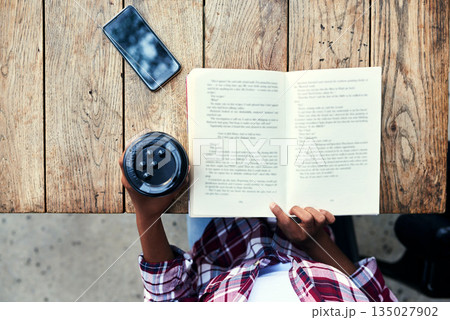 Woman, hands and book of student reading with coffee for literature on wooden table above at cafe. Top view of female person hand and story novel for knowledge, language or information at coffee shop Woman, hands and book of student reading with coffee for literature on wooden table above at cafe. Top view of female person hand and story novel for knowledge, language or information at coffee shop 135027902