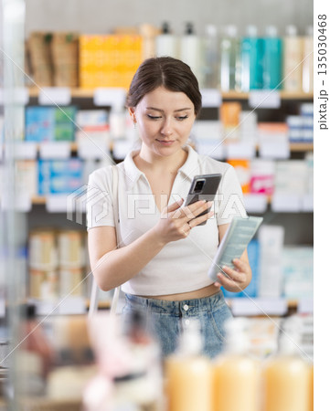 Young woman scanning qr code of cream Young woman scanning qr code of cream 135030468