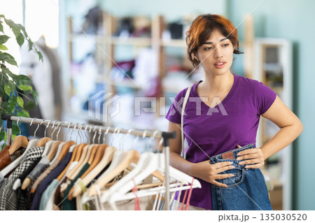 Young girl choosing jeans pantaloons in clothing store Young girl choosing jeans pantaloons in clothing store 135030520