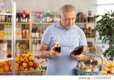 Mature man is choosing beer in grocery store Mature man is choosing beer in grocery store 135030587