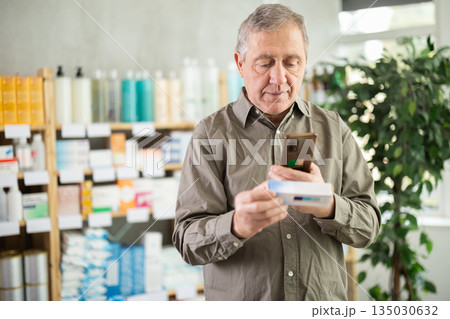 Elderly man scans ointment package Elderly man scans ointment package 135030632