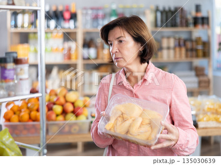 Mature woman choosing chicken in grocery store Mature woman choosing chicken in grocery store 135030639
