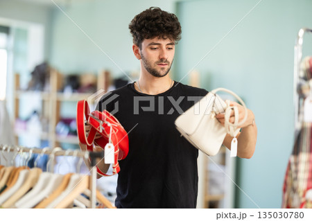 Young man chooses handbag in clothing store 135030780