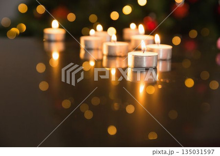 Lit tea light candles on glass table during christmas 135031597