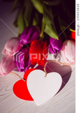 Colorful tulip bouquet is being shown in flat design on pale wooden surface with heart tags Colorful tulip bouquet is being shown in flat design on pale wooden surface with heart tags 135031619