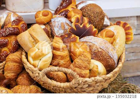 Woven basket filled with different types of freshly baked breads pastries arranged invitingly at local bakery Woven basket filled with different types of freshly baked breads pastries arranged invitingly at local bakery 135032218