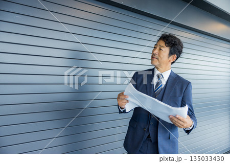 店舗物件の前で考えるビジネスマン 135033430