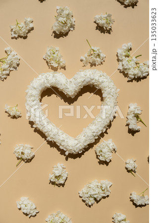 Heart made of white lilac flowers on pastel beige background. Still life romantic composition of Valentines day holiday copy space for your text invitation greeting card Heart made of white lilac flowers on pastel beige background. Still life romantic composition of Valentines day holiday copy space for your text invitation greeting card 135033623