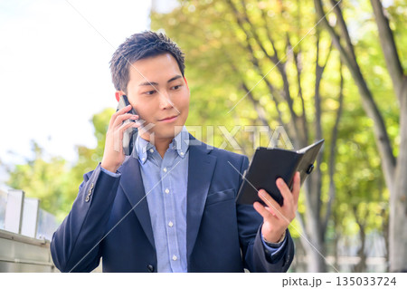 屋外で電話と手帳 135033724