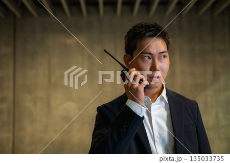 無線機で警戒・連絡する警備員の男性 無線機で警戒・連絡する警備員の男性 135033735