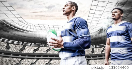 Determined young african american rugby player holding ball in stadium Determined young african american rugby player holding ball in stadium 135034400