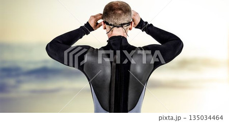Rear view of male swimmer wearing swimming goggles at beach 135034464