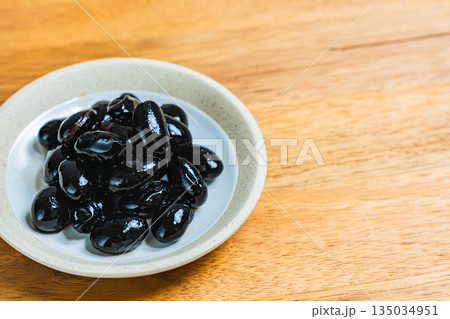 木目テーブルの上の小皿に盛られた黒豆 135034951