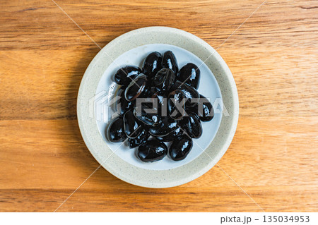 木目テーブルの上の小皿に盛られた黒豆 135034953